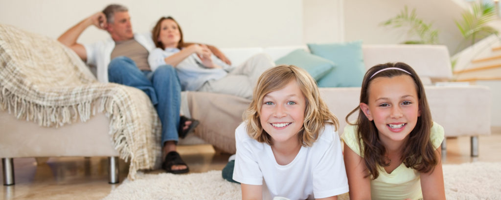 Smiling children laying on the floor while parents relax on the couch
