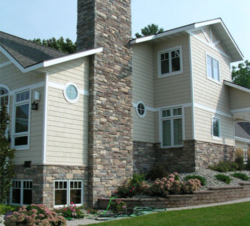 House with stone chimney and stone under the siding